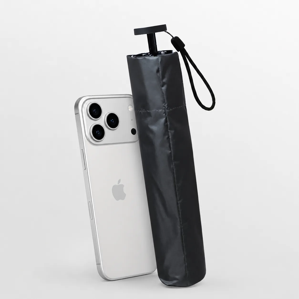 Compact mini lightweight folding umbrella shown beside a smartphone for size comparison