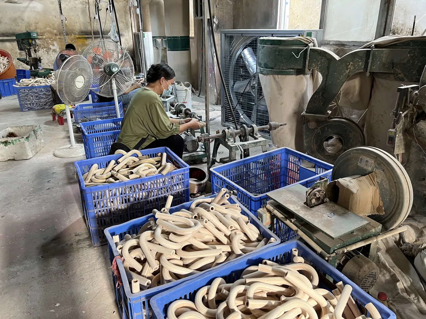 Worker processing curved wooden umbrella handles in a component workshop