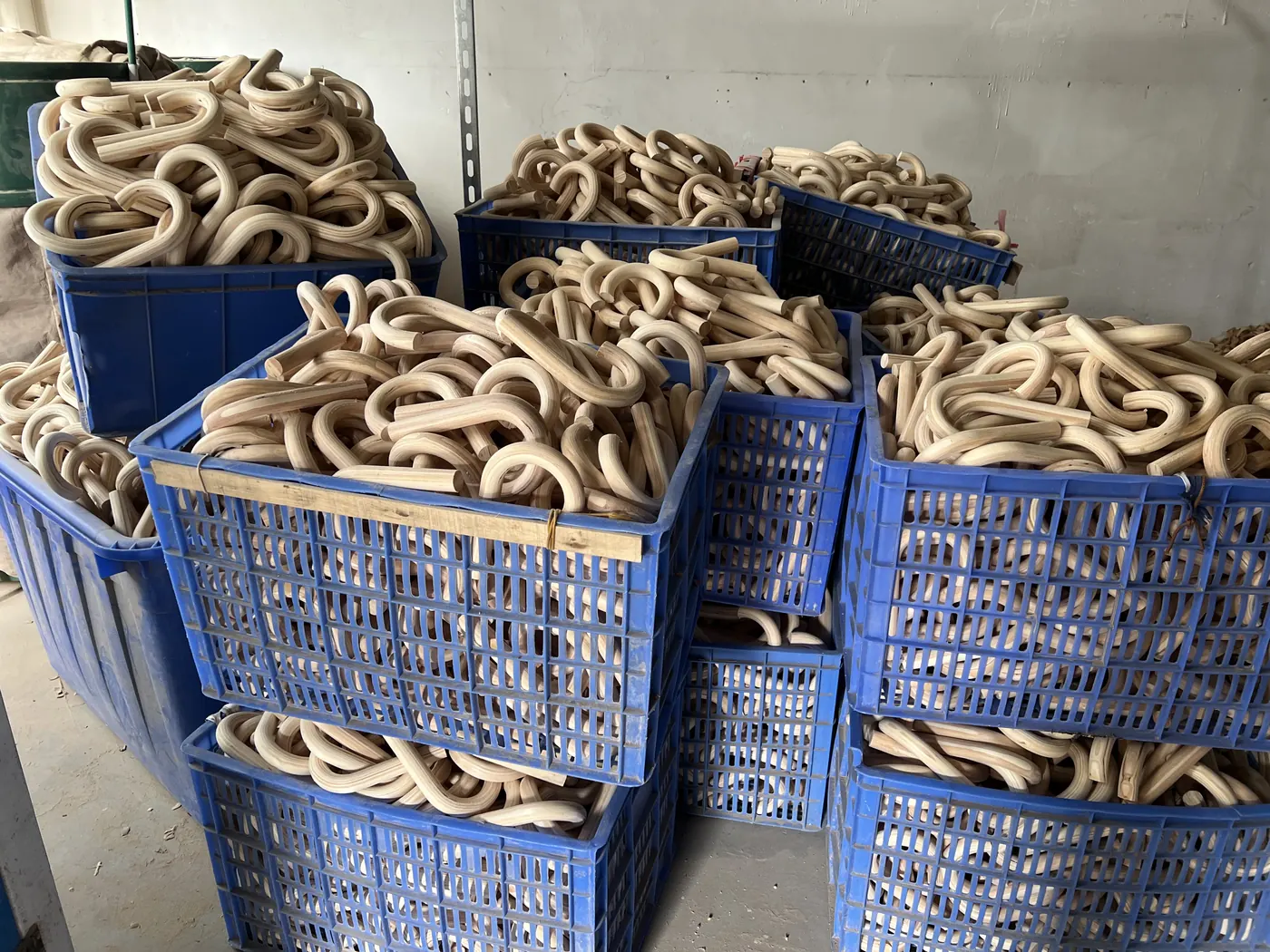 Unfinished curved wooden umbrella handles stored in crates at a component supplier