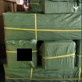 Green-wrapped packages secured with yellow straps at the freight warehouse, with the label redacted