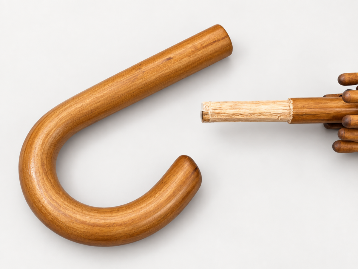 Detached curved wooden umbrella handle beside an exposed wooden shaft end