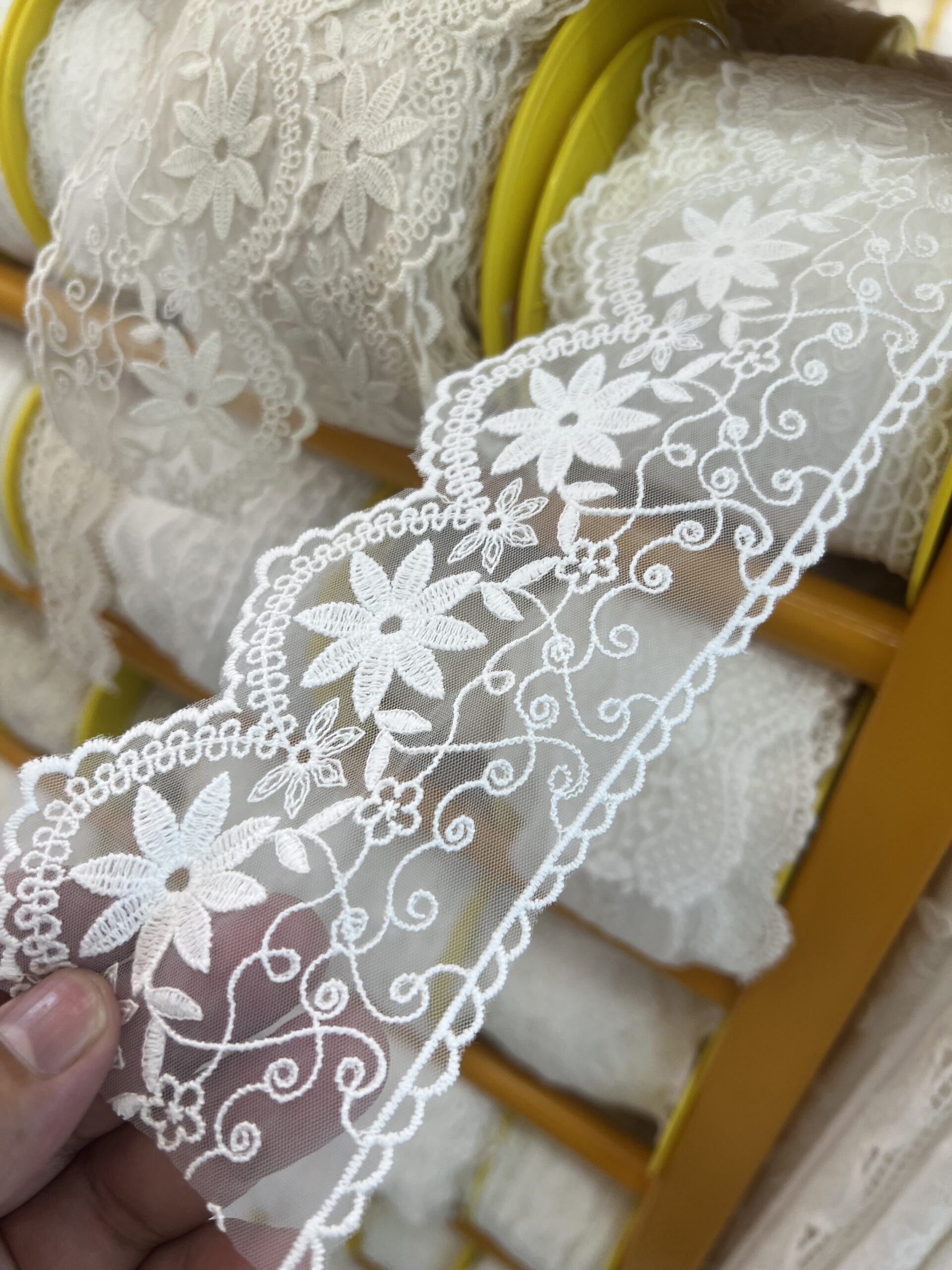 White floral lace trim being compared during material sourcing